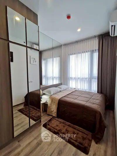 Modern bedroom with mirrored wardrobe and large windows in stylish apartment.