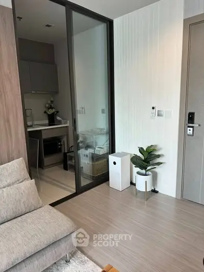 Modern living room with sleek design and compact kitchen area, featuring stylish decor and neutral tones.