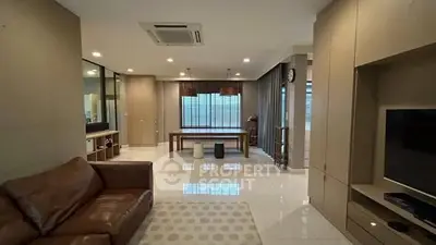 Spacious modern living room with leather sofa and dining area, featuring sleek design and ample natural light.