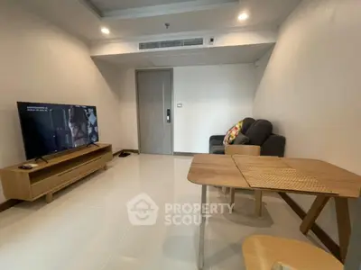 Modern living room with sleek furniture and large TV in a cozy apartment setting.