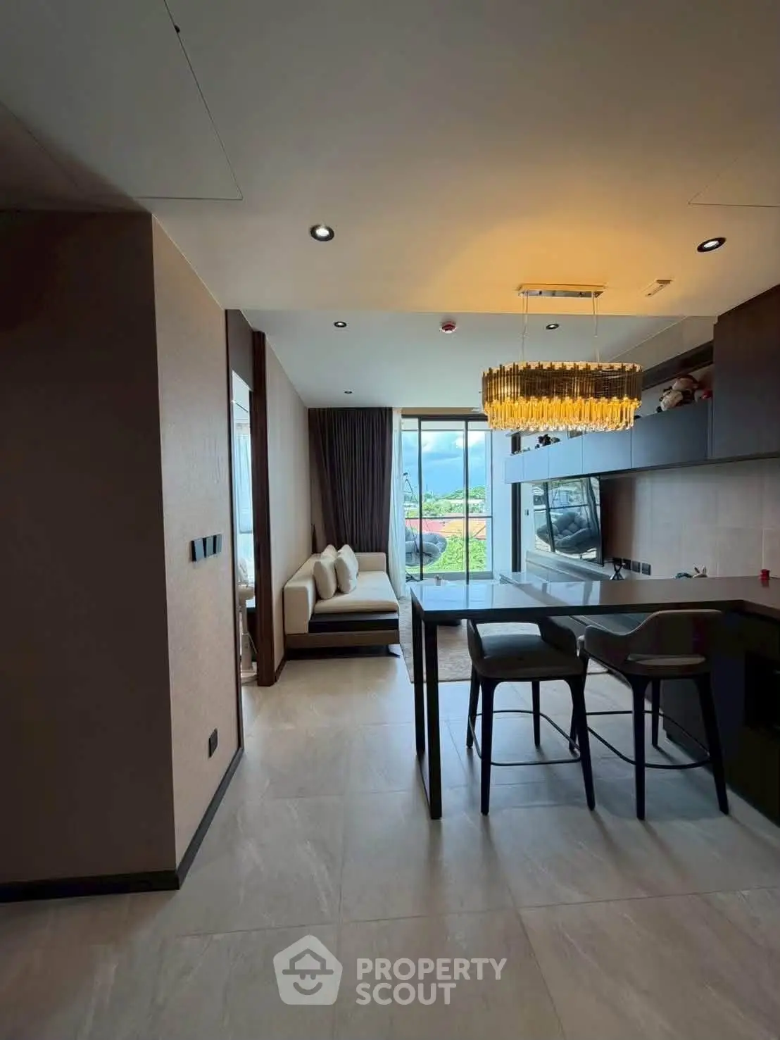 Modern open-layout living room with stylish chandelier and large windows offering natural light.