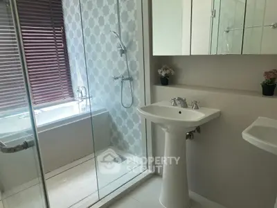 Modern bathroom with glass shower and bathtub, featuring elegant fixtures and stylish decor.