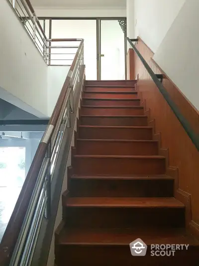 Spacious stairway with wooden steps and metal railings in modern building