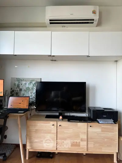 Modern living room with sleek furniture, TV, and air conditioning unit, perfect for tech-savvy homeowners.