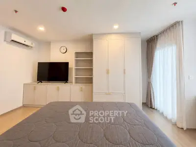 Spacious bedroom with modern decor, featuring a large bed, built-in wardrobe, and natural light from a window.