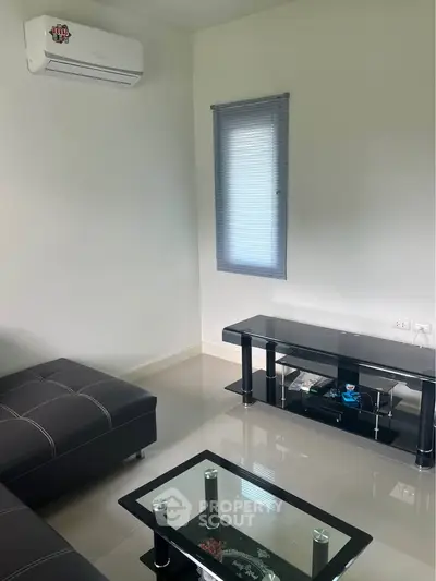 Modern living room with sleek black furniture and air conditioning, perfect for relaxation.