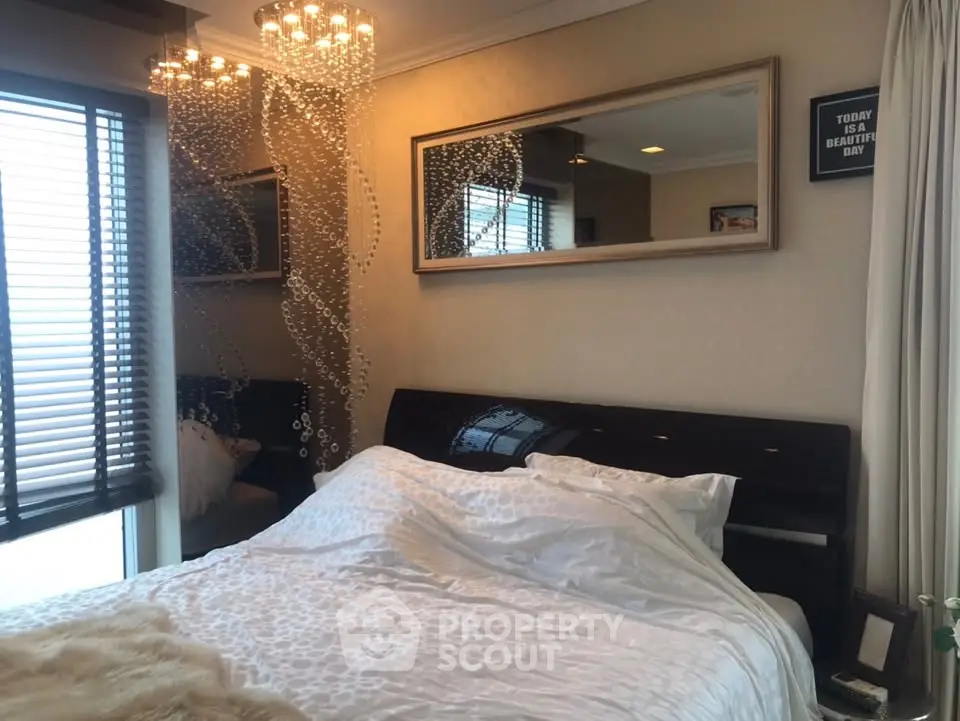 Luxurious bedroom with elegant chandelier and large mirror, offering a cozy and stylish retreat.