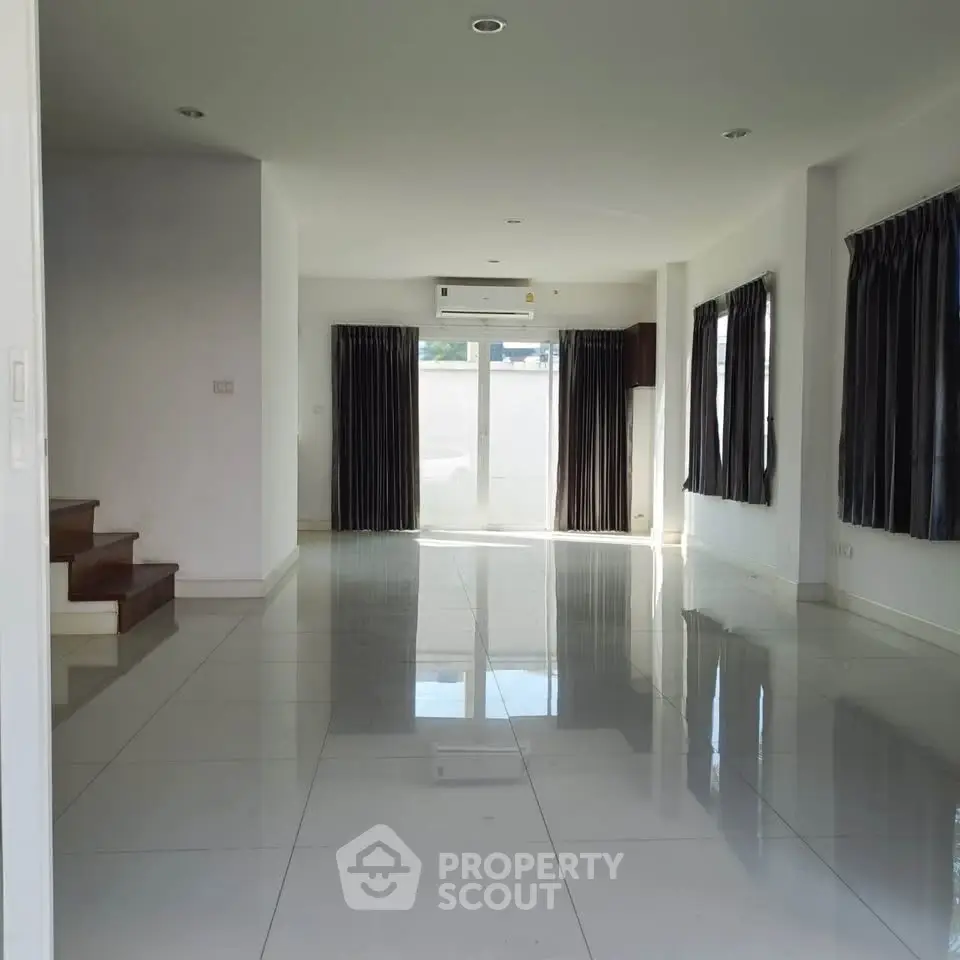 Spacious modern living room with glossy tile flooring and large windows for natural light.