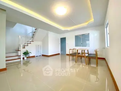 Spacious modern living area with elegant staircase and dining set, perfect for family gatherings.