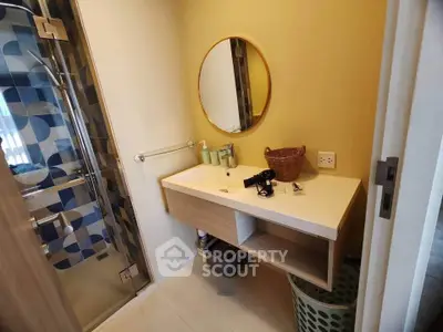 Modern bathroom with stylish round mirror and glass shower enclosure