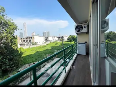 Spacious balcony with lush green view and city skyline, perfect for relaxation.