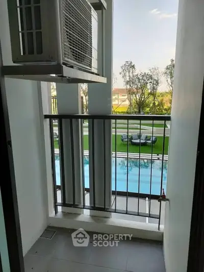 Charming balcony view overlooking a pristine pool and lush greenery, perfect for relaxation.