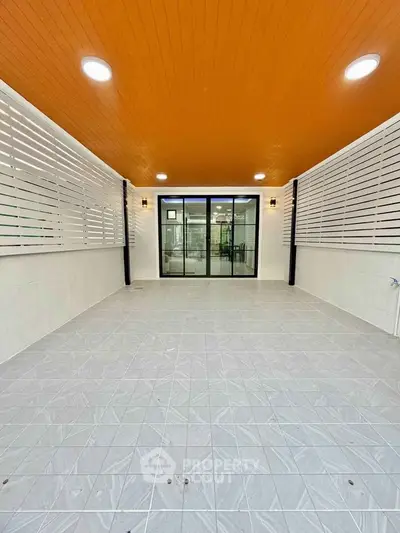 Spacious covered patio with modern design and sliding glass doors.