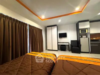 Modern bedroom with twin beds, kitchenette, and cozy seating area in stylish apartment.