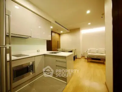 Modern open-layout kitchen with sleek appliances and cozy living area in a stylish apartment.