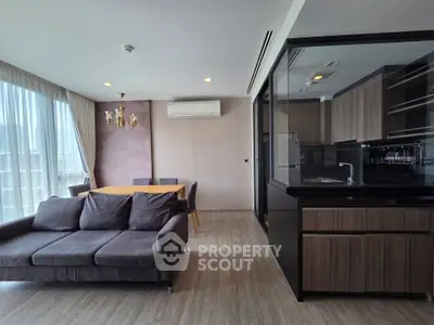 Modern living room with open kitchen, featuring elegant dining area and cozy sofa, perfect for urban living.