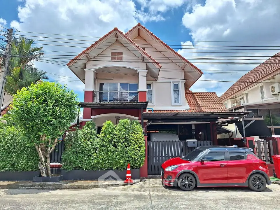 Charming two-story house with red roof and lush greenery in a serene neighborhood.
