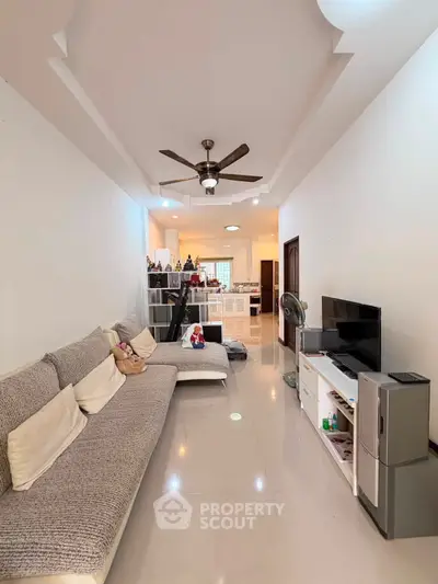 Spacious living room with modern decor and ceiling fan, perfect for relaxation and entertainment.
