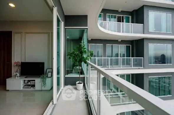 Modern apartment with spacious balcony and city view, featuring sleek glass railings and stylish interior.