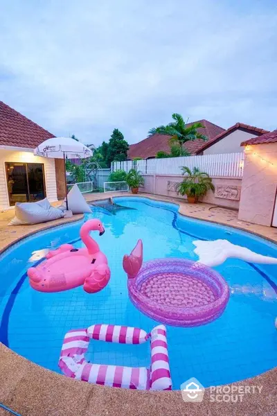 Charming backyard pool with playful inflatables and cozy seating area, perfect for relaxation and entertainment.