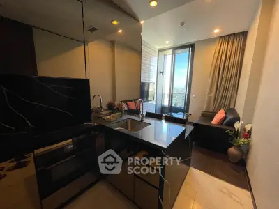 Modern kitchen with sleek black countertops and open layout leading to a cozy living area with city view.
