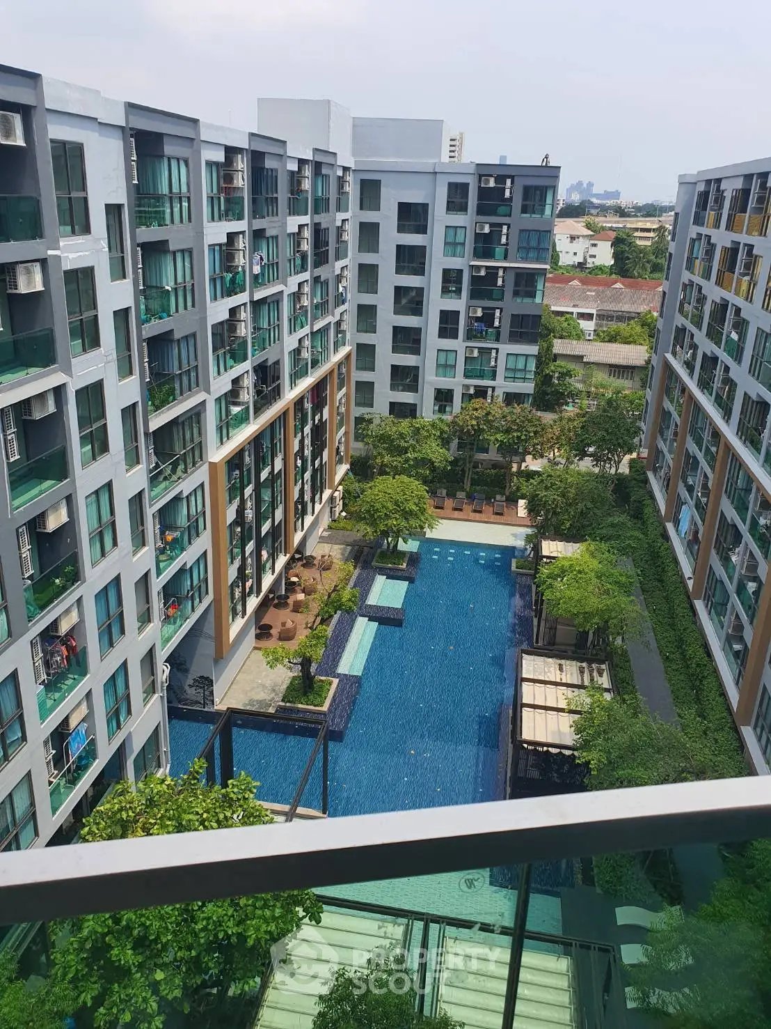 Modern condominium with pool view and lush greenery in urban setting.