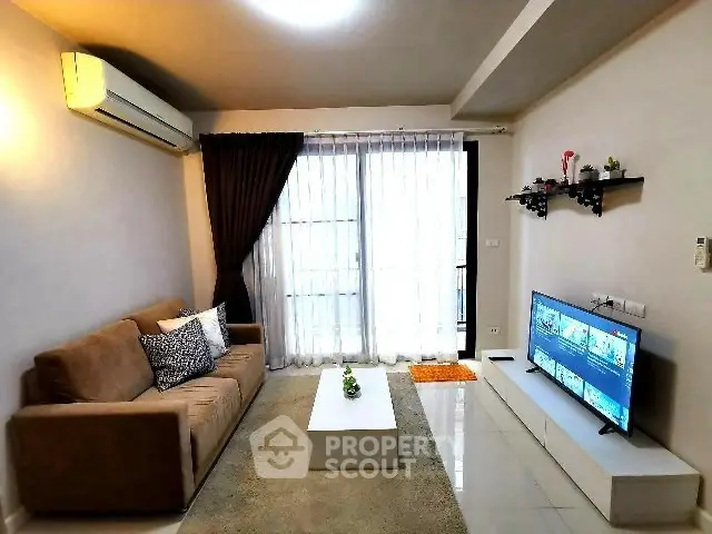 Modern living room with cozy sofa and large TV, featuring elegant decor and natural light.