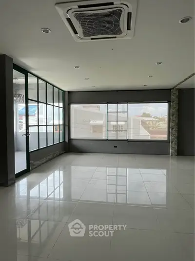 Spacious modern room with large windows and sleek tile flooring, perfect for versatile use.