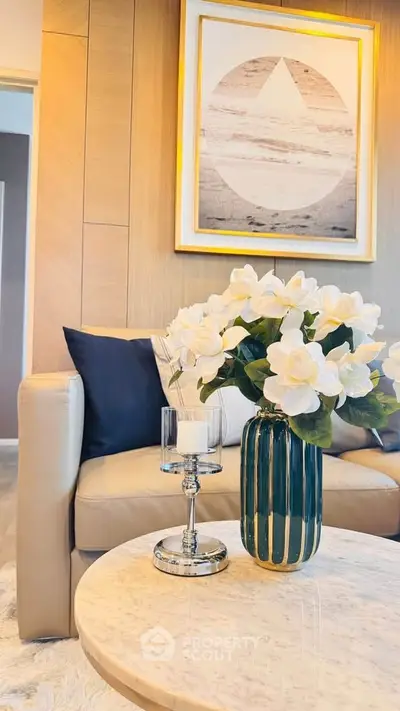 Elegant living room with modern decor, featuring a stylish sofa, chic artwork, and a decorative vase on a marble table.