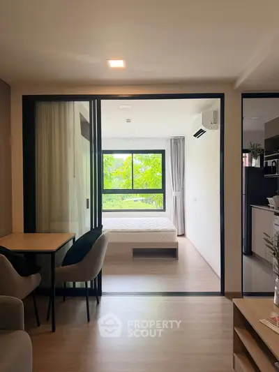 Modern apartment interior with open layout, featuring a cozy living area and a bright bedroom with large windows.