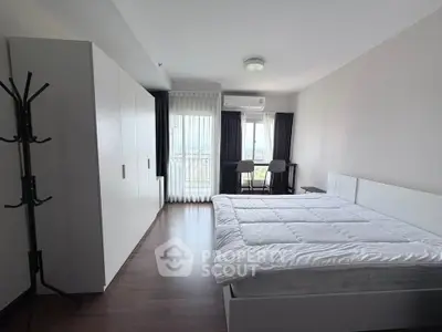 Spacious bedroom with modern decor and large window offering natural light and scenic views.