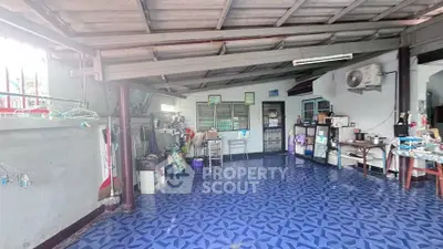 Spacious covered outdoor area with blue patterned flooring and household items, ideal for versatile use.