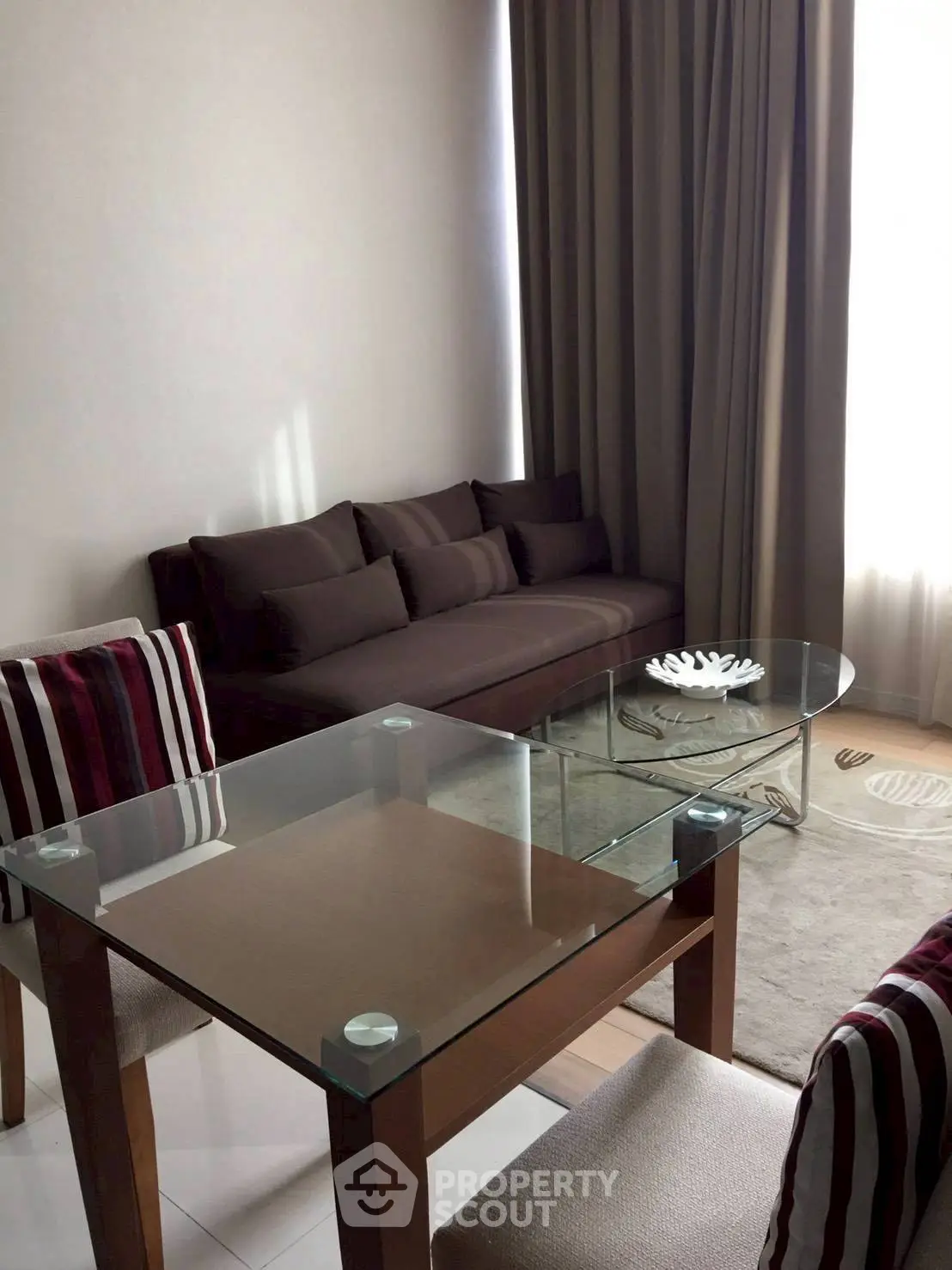 Modern living room with glass dining table and cozy sofa, perfect for urban living.