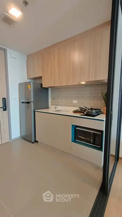 Modern kitchen with sleek cabinetry, stainless steel fridge, and built-in microwave in a stylish apartment.