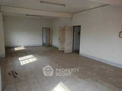 Spacious empty room with tiled flooring and multiple doors, ideal for customization.