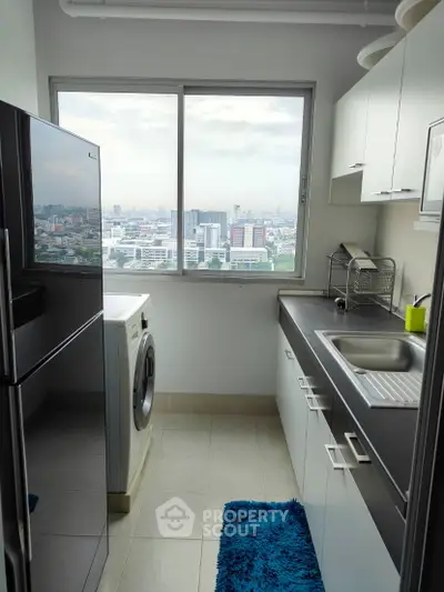 Modern kitchen with city view, featuring sleek cabinets, washing machine, and large window.