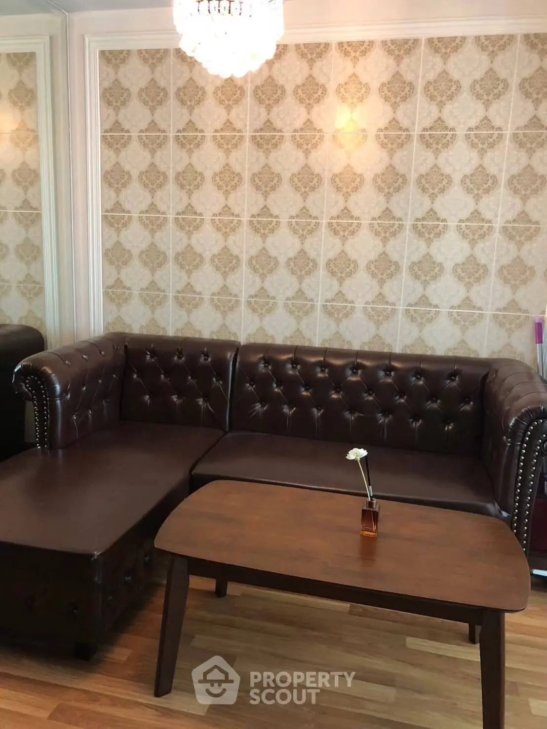 Elegant living room with brown leather sofa and wooden coffee table, featuring stylish wallpaper.