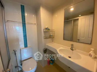Modern bathroom with sleek fixtures and ample lighting, featuring a large mirror and stylish tile accents.