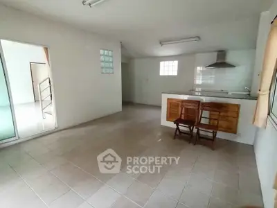 Spacious open-plan kitchen with tiled flooring and natural light.