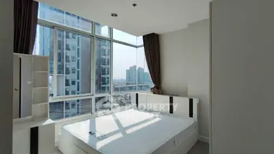 Modern bedroom with large windows offering stunning city views in a high-rise apartment.
