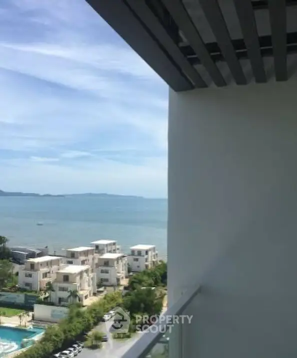Stunning ocean view from a modern balcony overlooking luxury villas and lush greenery.
