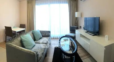 Modern living room with stylish furniture and large window offering natural light.
