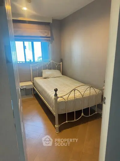 Cozy bedroom with single bed and window view, perfect for compact living spaces.