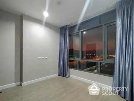 Spacious room with large window offering stunning city view at sunset