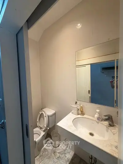 Compact bathroom with modern fixtures and marble flooring, featuring a sleek sink and toilet.