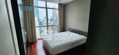 Modern bedroom with large window offering stunning city view in high-rise apartment.