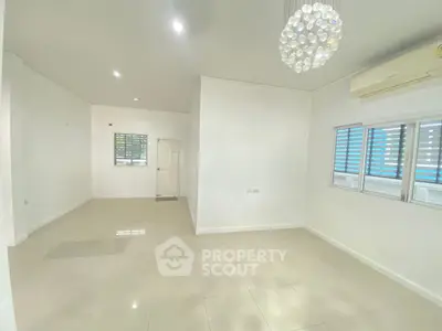 Spacious and bright living room with modern chandelier and air conditioning.