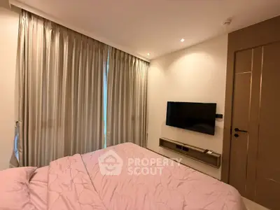 Cozy bedroom with modern decor and wall-mounted TV, featuring elegant curtains and soft lighting.
