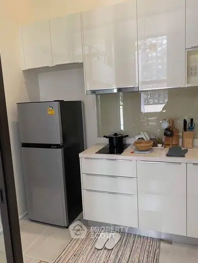 Modern kitchen with sleek white cabinets and stainless steel fridge, perfect for contemporary living.