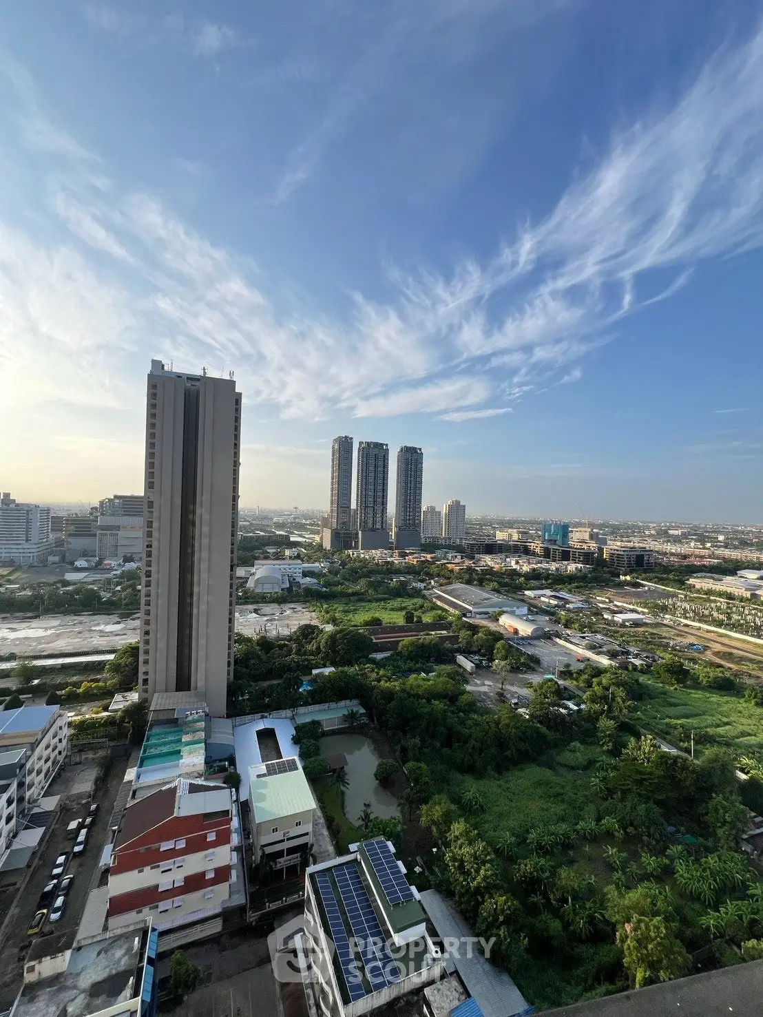 Stunning cityscape view with modern high-rise buildings and lush greenery under a clear blue sky.